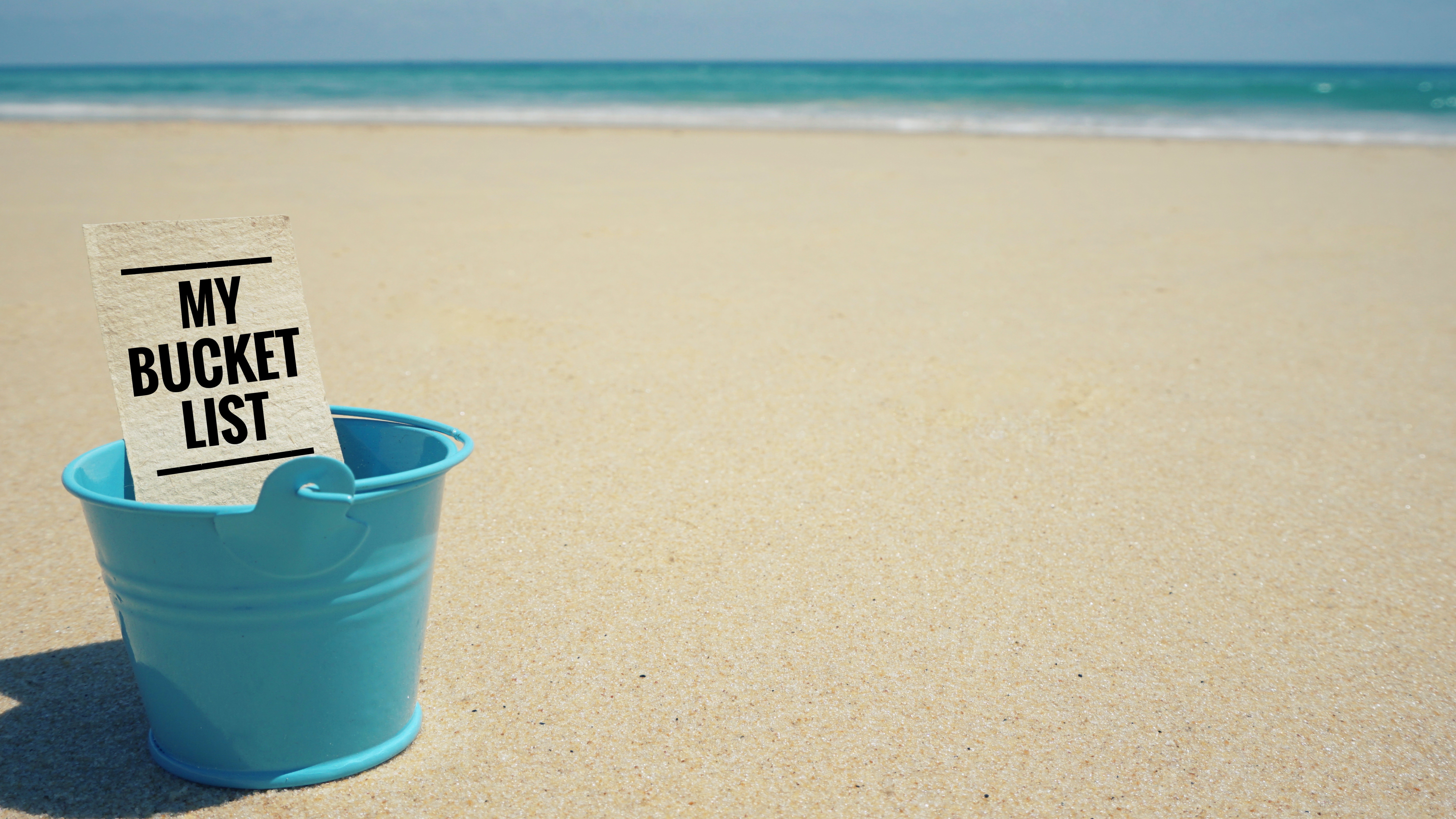 Strand mit Eimer und Bucket-List-Notiz – Sinnbild für erfüllte Wünsche